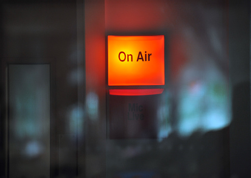 An illuminated 'On Air' sign outside a Radio/TV studio during a broadcast. Studio glass reflections
