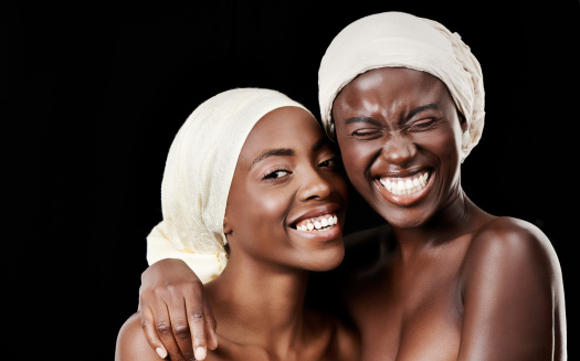 Studio portrait of two beautiful women wearing headscarves against a black background