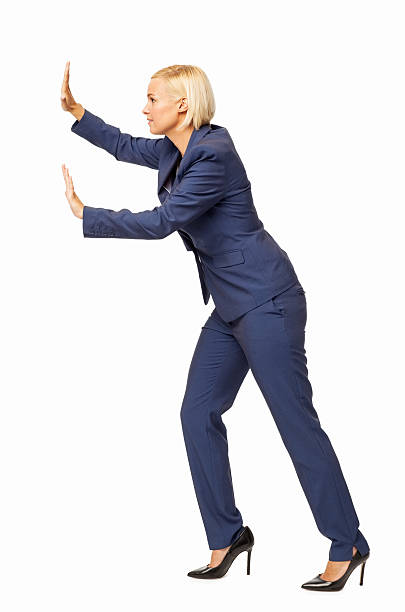Side View Of Businesswoman Pushing Invisible Wall Full length side view of businesswoman pushing invisible wall over white background. Vertical shot. pushing stock pictures, royalty-free photos & images