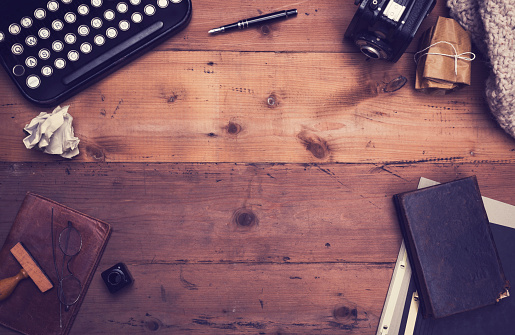 Vintage or retro styled hero header with typewriter, old camera and other old retro items on wooden table top office desk.