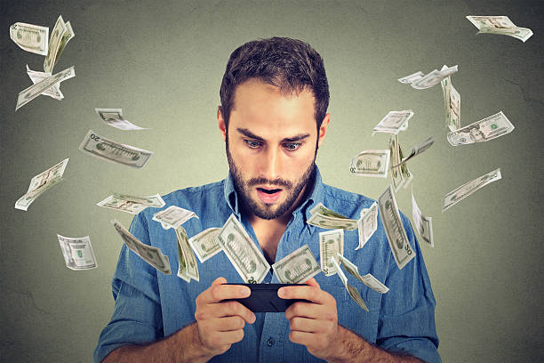 istock online banking. Shocked man using smartphone dollar bills flying away 503048388