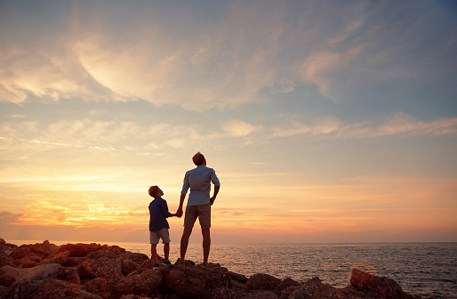 Father with son on the sea coast in sunset time