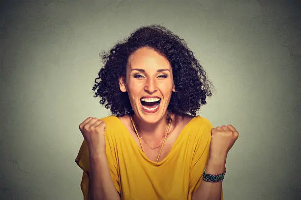 happy woman exults pumping fists ecstatic celebrates success on gray background