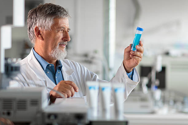 investigador senior masculino llevando a cabo investigaciones científicas en un laboratorio - scientist lab coat doctor male fotografías e imágenes de stock