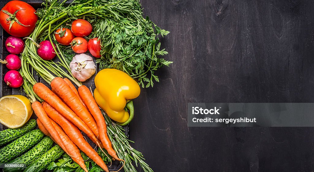 Colorful various organic farm vegetables  top view  border, place text Colorful various organic farm vegetables carrots cherry tomatoes, garlic, cucumber, lemon, pepper, radish, wooden spoon salt pepper colored, oil wooden rustic background top view  border, place text Vegetable Stock Photo