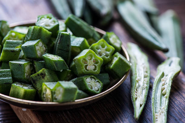 Farm fresh okra on wooden board Farm fresh okra on wooden board, whole and sliced Okra stock pictures, royalty-free photos & images