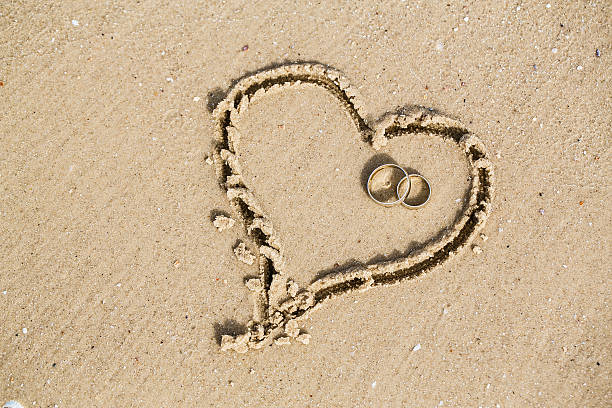 obrączki mieścić się w piasek serca - beach love heart shape two objects zdjęcia i obrazy z banku zdjęć