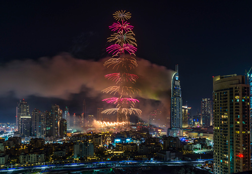 Dubai, UAE - December 31, 2015: Smoke billows from the Address Downtown Hotel (R), after it caught on fire hours earlier, past fireworks, near the Burj Khalifa, the world's tallest tower in Dubai, on January 1, 2015. Huge fire ripped through a luxury 63-storey hotel, the Address Downtown, where crowds were gathering to watch New Year's Eve celebrations. The cause of the blaze was not immediately known but the building was safely evacuated.