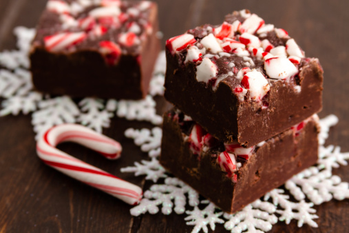 Holiday candy cane fudge pieces stacked on white glitter snowflake