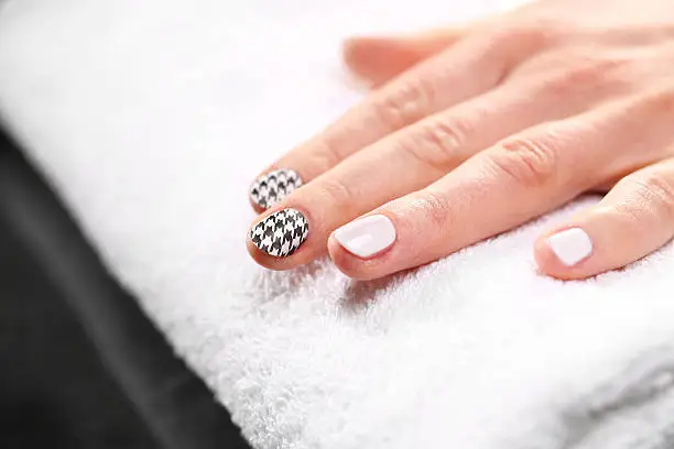 Woman's hand with fingernails painted in black and white checkered 