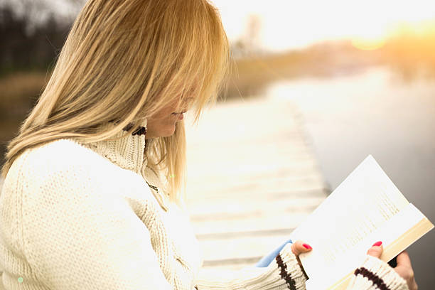 istock Woman reading a book by the lake 503082116