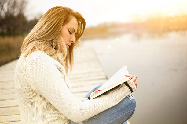 istock Woman reading a book by the lake 503082140