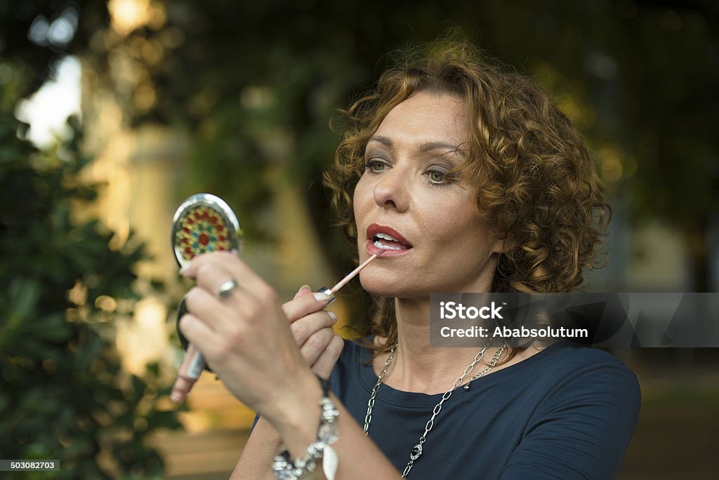 Beautiful Woman with Lipstick , Make up in City Park, Italy Portrait of beautiful mature woman applying lipstick, city park in Italy, Europe. Senior Adult Stock Photo