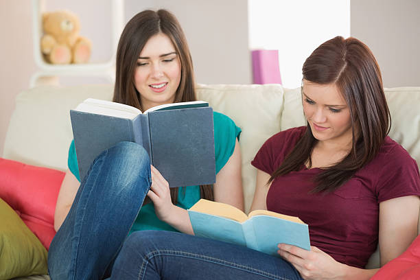 istock Two girls reading books on the couch 503082751