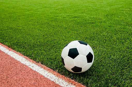The football is near line on the artificial grass soccer field in the stadium.