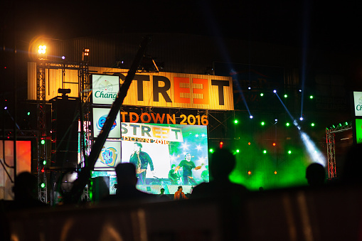 Bangkok, Thailand - December 31, 2015: Public new year concert at Street 23 mall on Ratchada Road in Bangkok. View from sidewalk to square in front of mall. TV crane is in scene. On stage band is performing. Several bands are entertaining night.