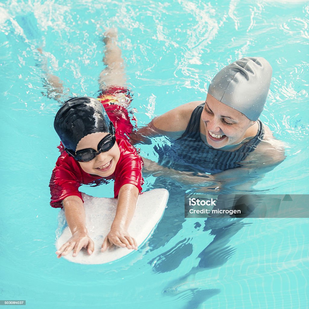 Learning swimming Cheerful boy learning to swim with swimming board Learning Stock Photo