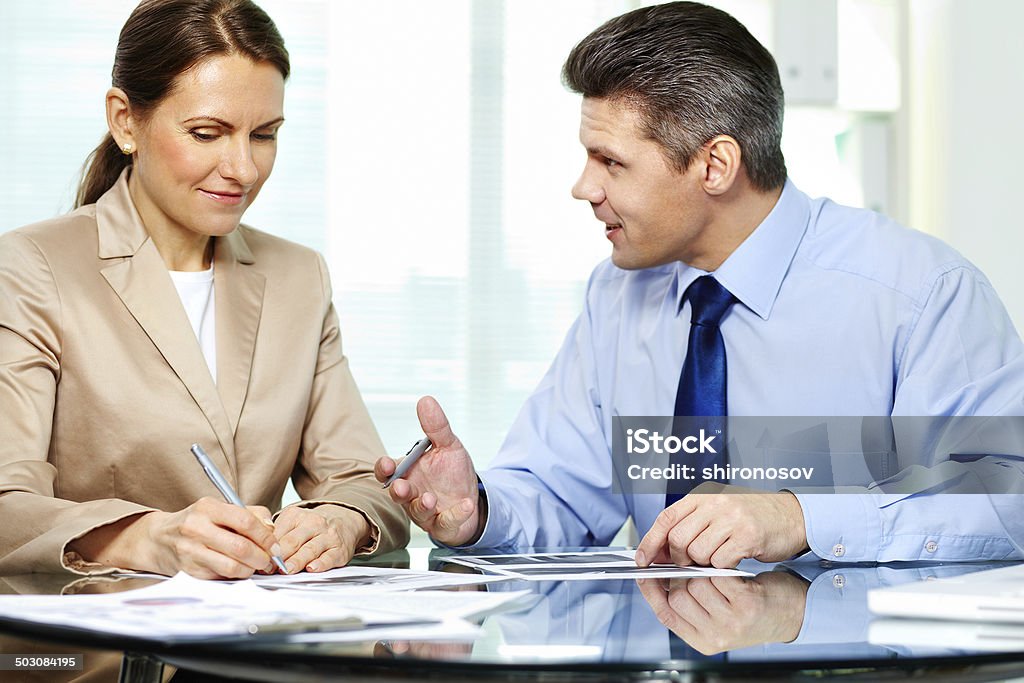 Discussing papers Business partner explaining new strategy to elegant business woman Adult Stock Photo