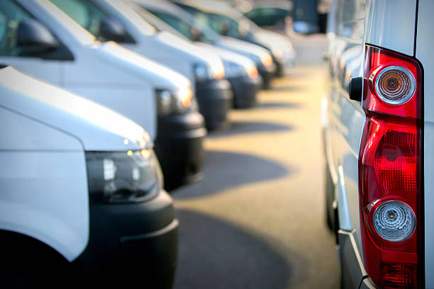 Large group of Vans / Transporters A large group of delivery vans / transporters after work in a parking lot at sunset. The focus is on the right side of the picture, it shows a vans left rear light. The outdoor lighting is switched on. The vans transport/deliver many packages and run removals. more service vehicles, and cars in my portfolio light commercial vehicle stock pictures, royalty-free photos & images