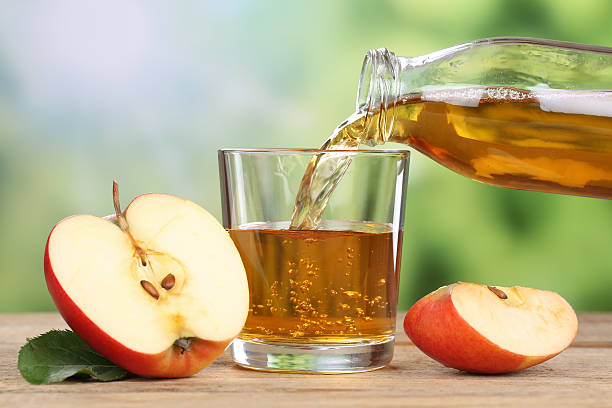 Apple juice pouring from red apples into a glass stock photo
