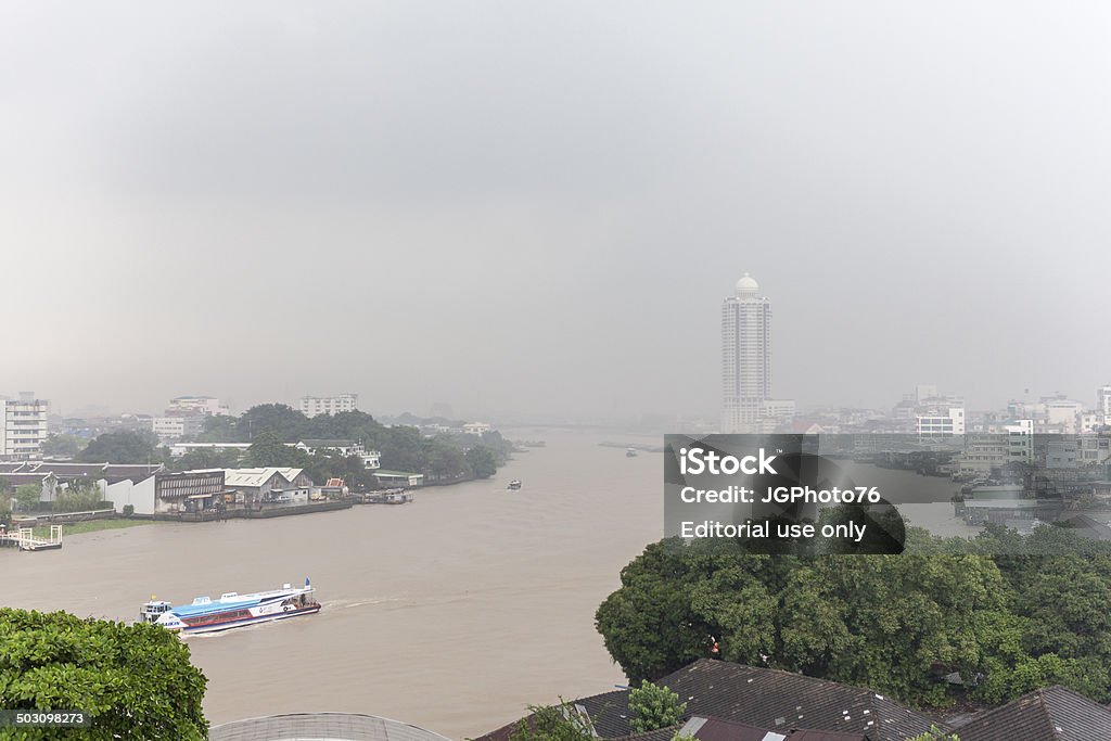 Rainy season in Bangkok Bangkok, Thailand - May 27, 2011: After a rain during the monsoon season in Bangkok, it is due to the humidity thick fog over the Chao Phraya River and the city. Many buildings are difficult to detect. Meanwhile retracts Chao Phraya Tourist Boat, tourists down the river. Aerial View Stock Photo
