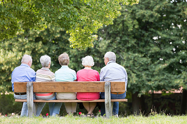 gruppe von senior erwachsener auf bank im park - senior adult women park bench 70s stock-fotos und bilder