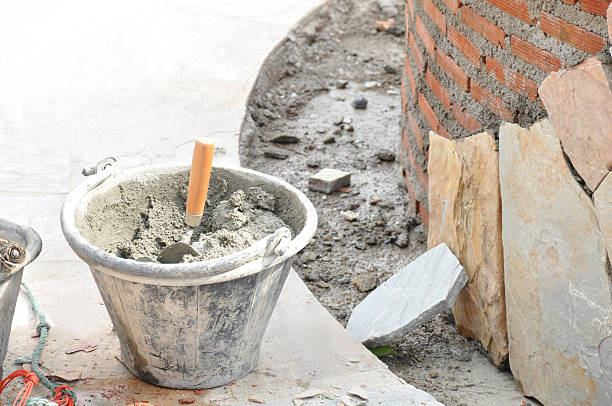 istock Bucket of mortar with trowel beside constructing brick wall 503102477