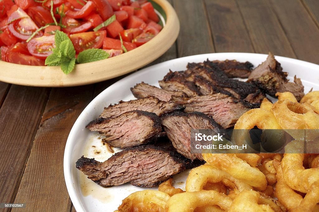 Filete de costilla con papas fritas anillos de cebolla y ensalada - Foto de stock de Alimento libre de derechos