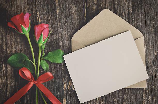 Blank white greeting card with red rose Blank white greeting card with brown envelope and red rose flowers with ribbon bow on wooden table with vintage and vignette tone - Valentine and love concept pink envelope stock pictures, royalty-free photos & images