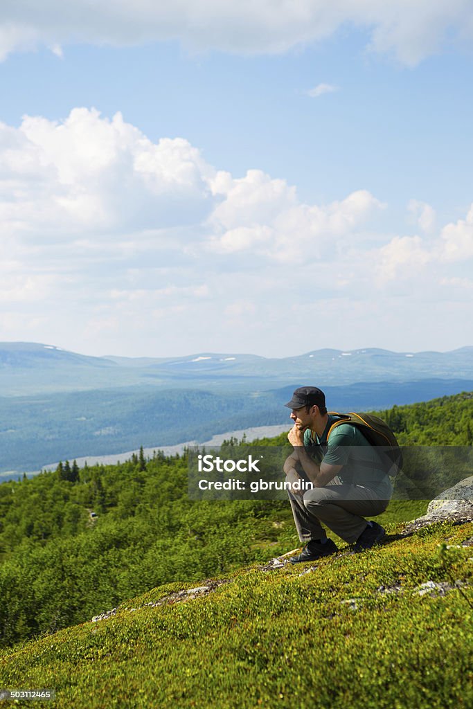 Samotny mężczyzna siedzący na mountain top - Zbiór zdjęć royalty-free (Chmura)