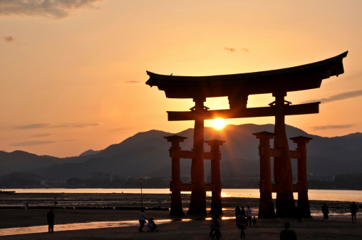 Miyajima, Japan - April 27, 2009: The Great tori of Itsukushima shinto shrine in the sunset on Miyajima Island in Hiroshima Prefecture. Miyajima island is a very popular touristic destination in Japan and the Great Tori is its most famous attraction.