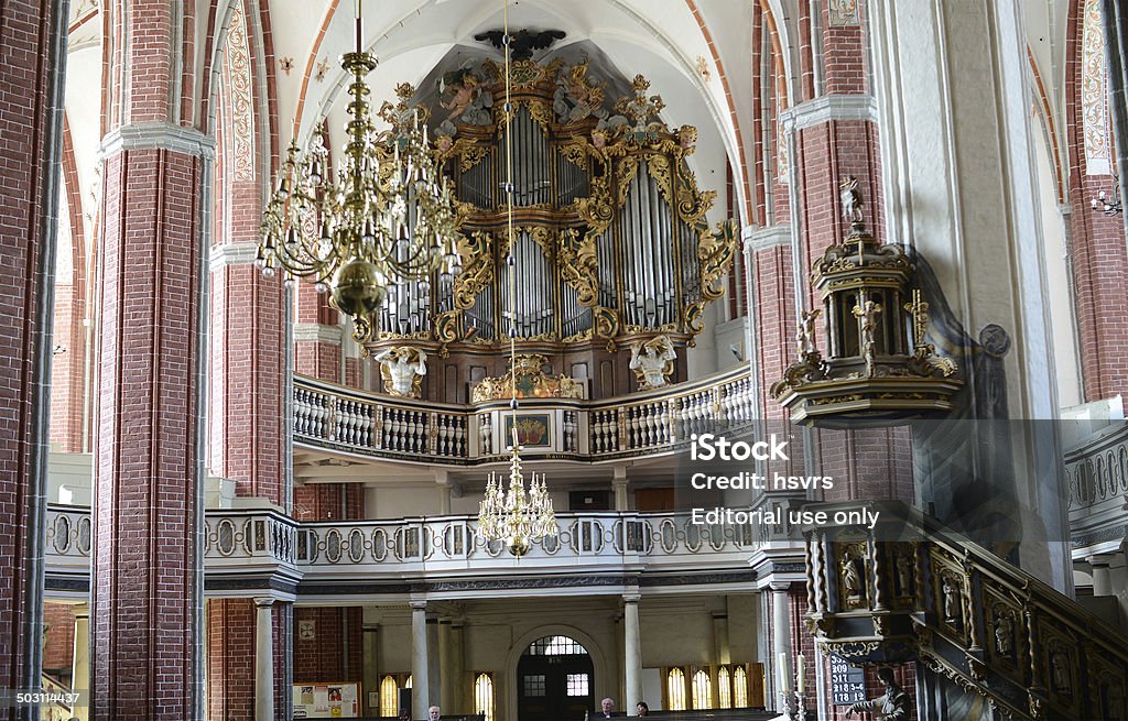 St. Katharinen Church (Brandenburg, Germany) Brandenburg an der Havel, Germany - July 16, 2014: Pipe orange (build 1726) of St. Katharinen Curch (Brandenburg an der Havel) in Brandenburg an der Havel (Brandenburg, Germany) with its gold ornaments. People sitting on the pews and look at the interior with its altar and the large pipe organ and decorated with carvings pulpit. Arch - Architectural Feature Stock Photo