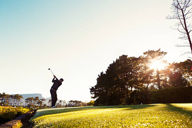 istock Young golfer, silhouetted against morning sun, tees off 503116149