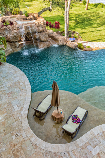 A custom swimming pool with lounge area as well as waterfall and slide.