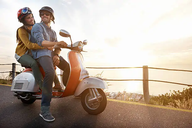 A shot of a young couple riding on a scooter