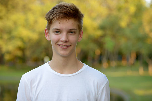 teenager boy sonriendo al aire libre en el parque - t shirt child white portrait fotografías e imágenes de stock