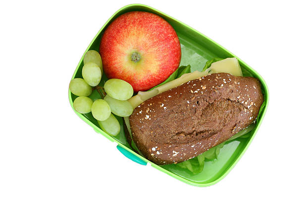 обед box containing коричневый сыр ролик, фрукты изолированные на белом - lunch bag apple brown стоковые фото и изображения