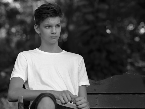Caucasian teenager boy sitting outdoors in park