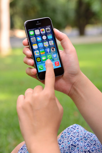 İstanbul, Turkey - July 24, 2014: Woman hands holding and touching an Apple iPhone 5 s in a park. iPhone 5 s is a smart phone produced by Apple Computer, Inc