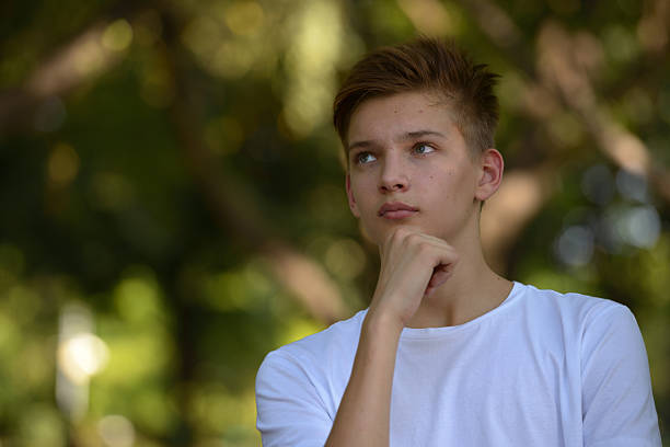 Caucasian teenager boy thinking outdoors in park