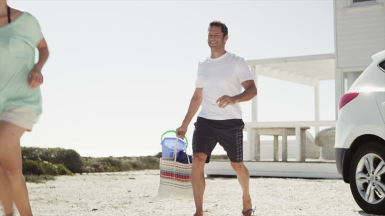 Family unpacking car and walking toward beach