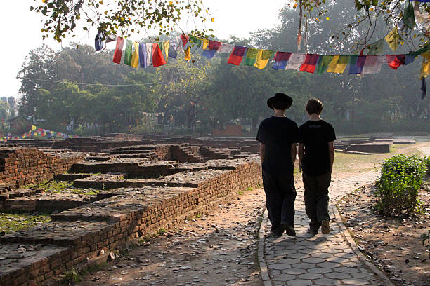Nepal: Walk Through Lumbini Lumbini, Nepal - March 15, 2011: A pair of visitors take a contemplative walk by the archeological site of Ashoka's monasteries (3rd Century BC) at the site of the Buddha's birth in Lumbini. It is one of the major pilgrimage destinations for Buddhists (along with Sarnath, Kushinagar, and Bodh Gaya). lumbini nepal stock pictures, royalty-free photos & images