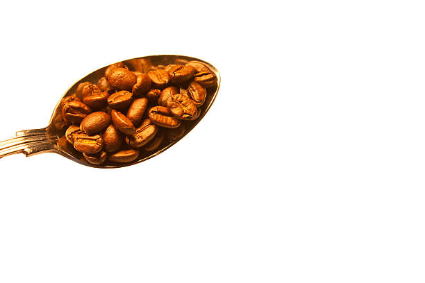 A tablespoon full of gorgeous coffee beans.  Taken on a white background.