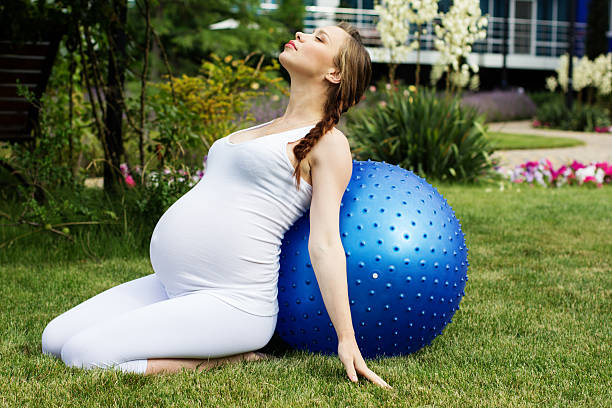 妊娠中の女性は美しい公園でリラックス。 - human pregnancy prenatal care relaxation exercise ball ストックフォトと画像