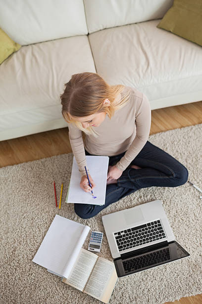 istock Blonde doing homework and sitting on floor using laptop 503138939