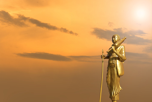 Golden Buddha statue on sunset sky background