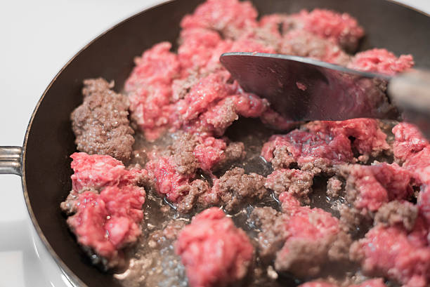 raw pink ground beef cooking in black pan
