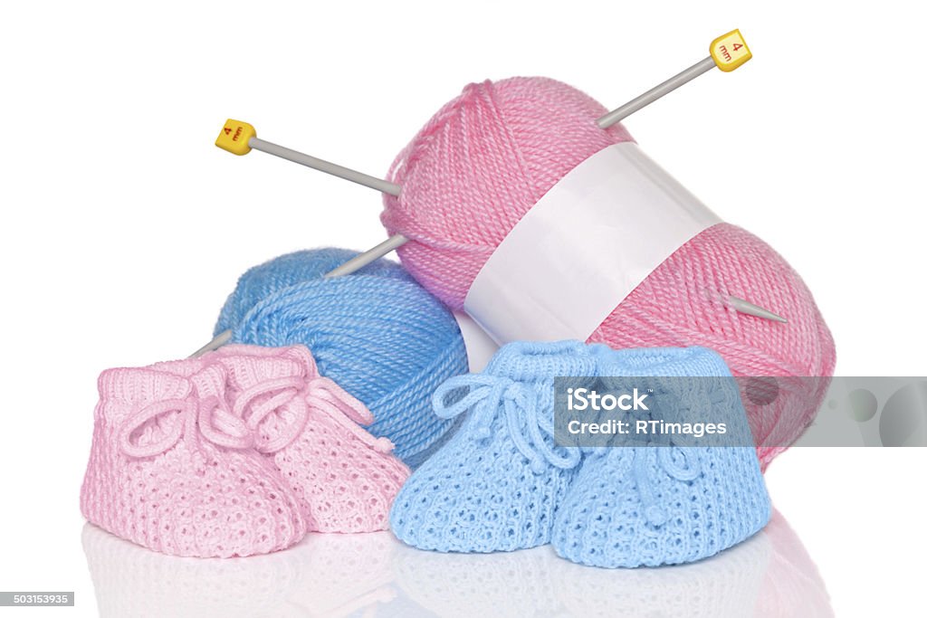 Baby booties with wool and knitting needles Knitted baby booties with blue and pink wool plus knitting needles, isolated on a white background. Baby Booties Stock Photo