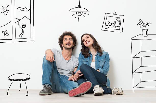 Happy Couple Dream New Home Portrait Of Happy Young Couple Sitting On Floor Looking Up While Dreaming Their New Home And Furnishing two people thinking stock pictures, royalty-free photos & images