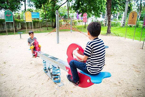 piccolo ragazzo giocare avanti insieme nel parco - totter foto e immagini stock